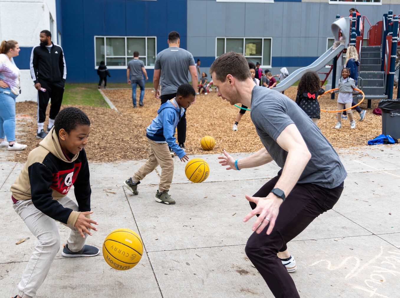 student and adult playing basketball