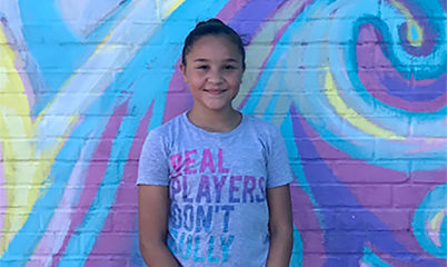 girl smiling in front of mural