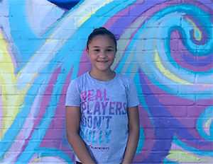 girl smiling in front of mural