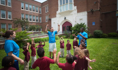 Coaches leading students in game outdoors