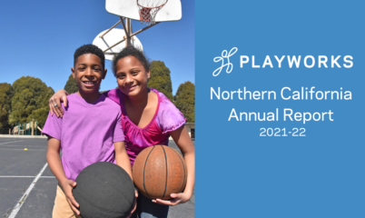 A boy and girl holding basketballs on a playground.